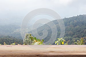 Wooden table light brown color with of mountain and fog a background. For montage product display or design key visual layout