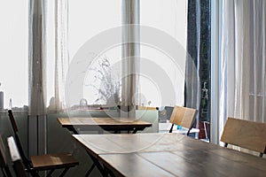 Wooden table, modern chairs and white curtain. Interior design of stylish dining room restaurant