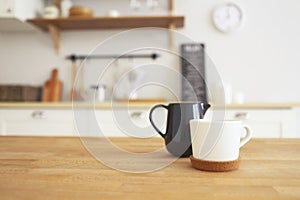 Wooden table with mug and milk jug with blurred kitchen background