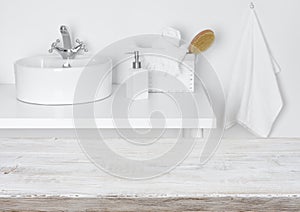 Wooden table over blurred domestic bathroom washbowl background