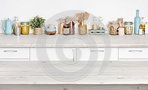 Wooden table over blurred kitchen furniture shelf with food ingredients