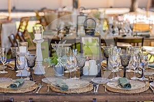 Wooden table with plates, cutlery and decoration for a boho hipster and vintage style event or wedding