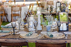 Wooden table with plates, cutlery and decoration for a boho hipster and vintage style event or wedding