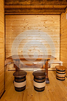 Wooden table with small wooden stools in the shape of wine barrels around in the room.