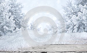 Wooden table with snowdrifts over blurred abstract winter landscape background