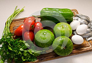 Wooden table with some vegetables, zucchinis, tomatoes, parsley, green pepper  and eggs