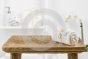 Wooden table with spa towel on blurred bathroom shelf background