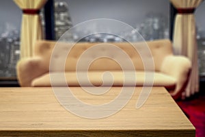 Wooden table with space for your product or text. Blurred bright and nice cozy home interior background with a beige sofa