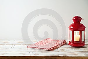 Wooden table with tablecloth and lantern over white wall background.  Christmas and New Year mock up for design and product