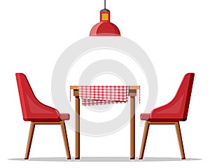 Wooden table with tablecloth, two chairs and lamp.