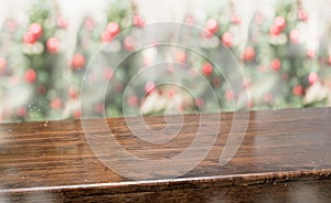 Wooden table top with abstract blur christmas tree red decor ball and snow fall background with bokeh light,winter Holiday