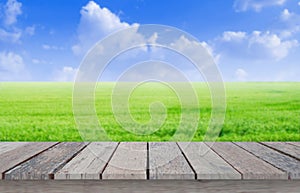 Wooden table top on blur rice field with blue sky background in morning atmosphere.For montage product display or design key