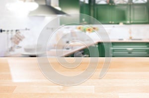 Wooden table top on a blurred background of the kitchen furniture shelves, range hood, and sink. can be used to display