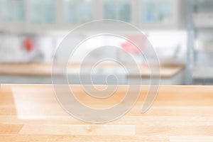 Wooden table top on a blurred background of the kitchen furniture shelves, range hood, and sink. can be used to display