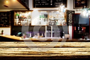 Wooden table top with blurred bar background. Space for advertising products.