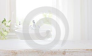 Wooden table top on blurred bathroom sink and curtained window photo