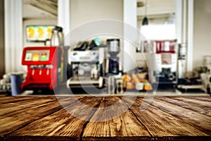 Wooden table top with blurred coffee express and juice squeezer and bar background. Space for advertising products.