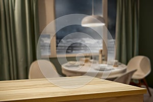 Wooden table top with blurred home interior background. Snowy winter outside the window.