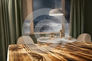 Wooden table top with blurred home interior background. Snowy winter outside the window.