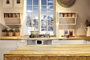 Wooden table top with blurred kitchen interior background. Snowy winter outside the window.