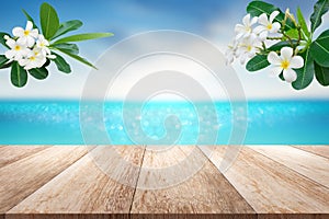 Wooden table top with blurry sea sun sky scenery decorate with plumeria flower branch tropical summer background