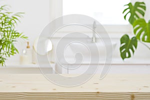 Wooden table top and defocused bathroom sink counter as background