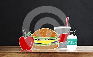 Wooden table top with drawing breakfast, Hamburger, apple, juice and milk, on black wall backgrounds