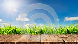 Wooden table top on green grass field and blue sky with white clouds background