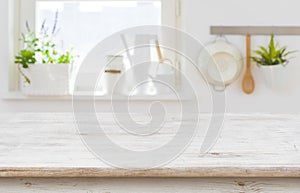 Wooden table top over blurred kitchen interior with copy space