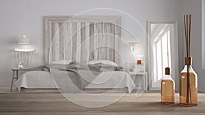 Wooden table top or shelf with aromatic sticks bottles over blurred scandinavian bedroom with homemade headboard, white architectu photo