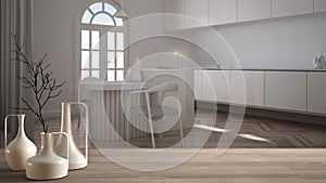 Wooden table top or shelf with minimalistic modern vases over blurred classic white kitchen with island and chairs, herringbone