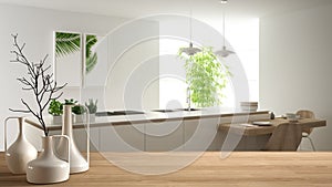 Wooden table top or shelf with minimalistic modern vases over blurred modern white kitchen with wooden details and parquet floor,