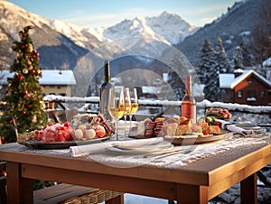 wooden table with two bottles of wine, glasses, food, dishes against the backdrop of snow-capped mountains