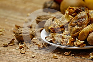 Dried fig and whole and cracked walnuts on white ceramic plate