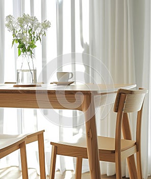 A wooden table with a vase of flowers and a cup of coffee on it.