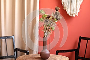 On wooden table are a vase of flowers in room. Cozy scandinavian home interior decor.