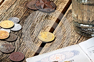 A wooden table on which is a glass and coins of the USSR with a military soldier ticket