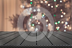 Wooden tabletop and blurred christmas tree in interior. Xmas background for display your products.