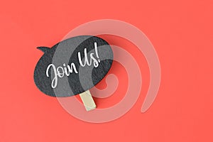 Wooden tag written with text JOIN US over red background