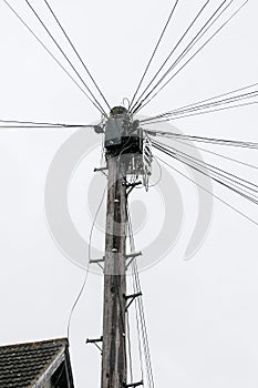 Wooden telephone pole with multiple communication cables and wires against cloudy sky