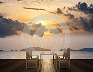 Wooden terrace with dining table and chairs on tropical ocean view in sunset