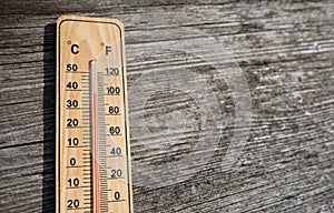 Wooden thermometer with red measuring liquid showing high temperature over 32 degrees Celsius on sunny day