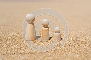 Wooden three figures of people on the sand of beach with sea view. Concept of happy family with two kids on holiday.