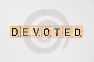 Wooden tile spelling the word devoted isolated on a white background