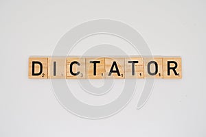 Wooden tile spelling the word dictator isolated on a white background