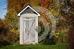 Wooden toilet backhouse at the edge of the forest at fall