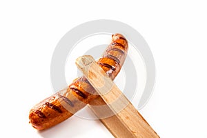 Wooden tongs holding a seared, barbecued sausage