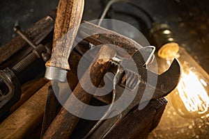 Wooden tool box of used hand tools with old and dirty, rusty wrenches, hammers and old light bulb