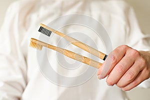 Wooden toothbrush on a white background in the hands of a woman.