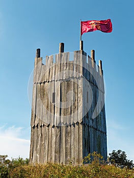 Wooden tower of viking village with viking flag waving against clear blue sky